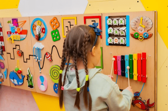 Child Engaging With Tactile Sensory Wall Panels For Motor Skill Development
